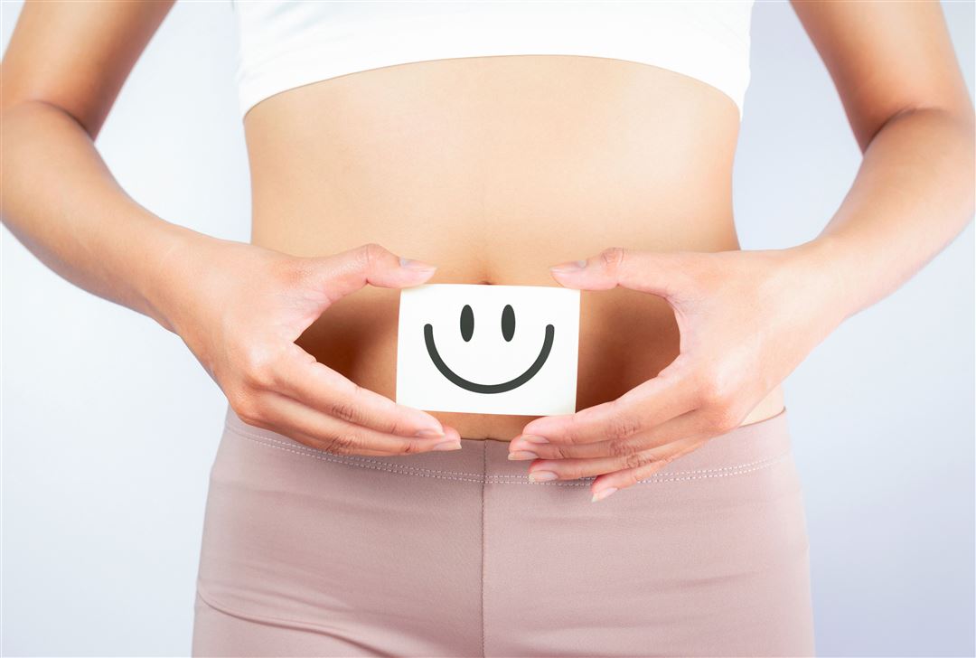 Oberk&ouml;rper einer Frau, h&auml;lt ein K&auml;rtchen mit Smiley von ihrem Bauch