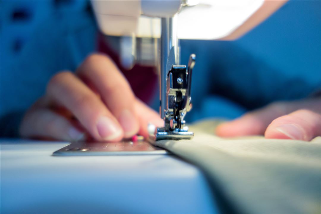 H&auml;nde einer n&auml;henden Person und N&auml;hmaschine in Nahaufnahme