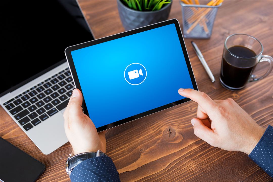 M&auml;nnliche Hand startet eine Videokonferenz auf einem Tablet.