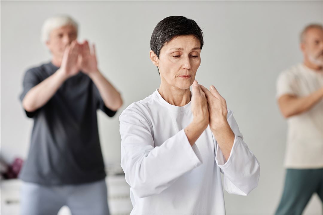 Frau praktiziert Qigong-&Uuml;bung in einer Kleingruppe
