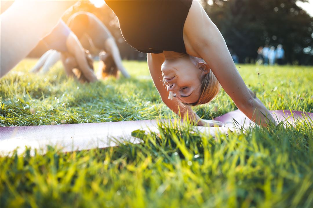 Blonde Frau praktiziert in einer Gruppe Yoga-&Uuml;bungen im Freien