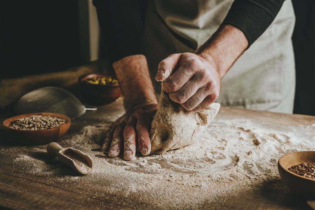 Mann knetet Brotteig auf einem Holztisch