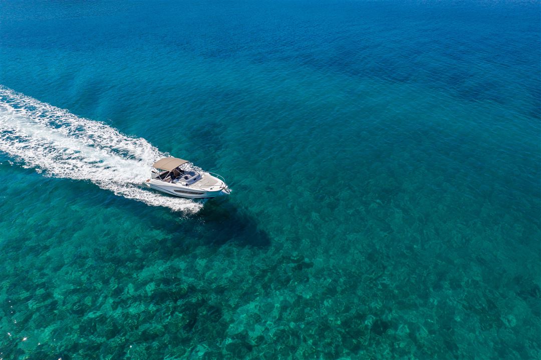 wei&szlig;es Sportboot f&auml;hrt &uuml;ber t&uuml;rkisblaues Wasser