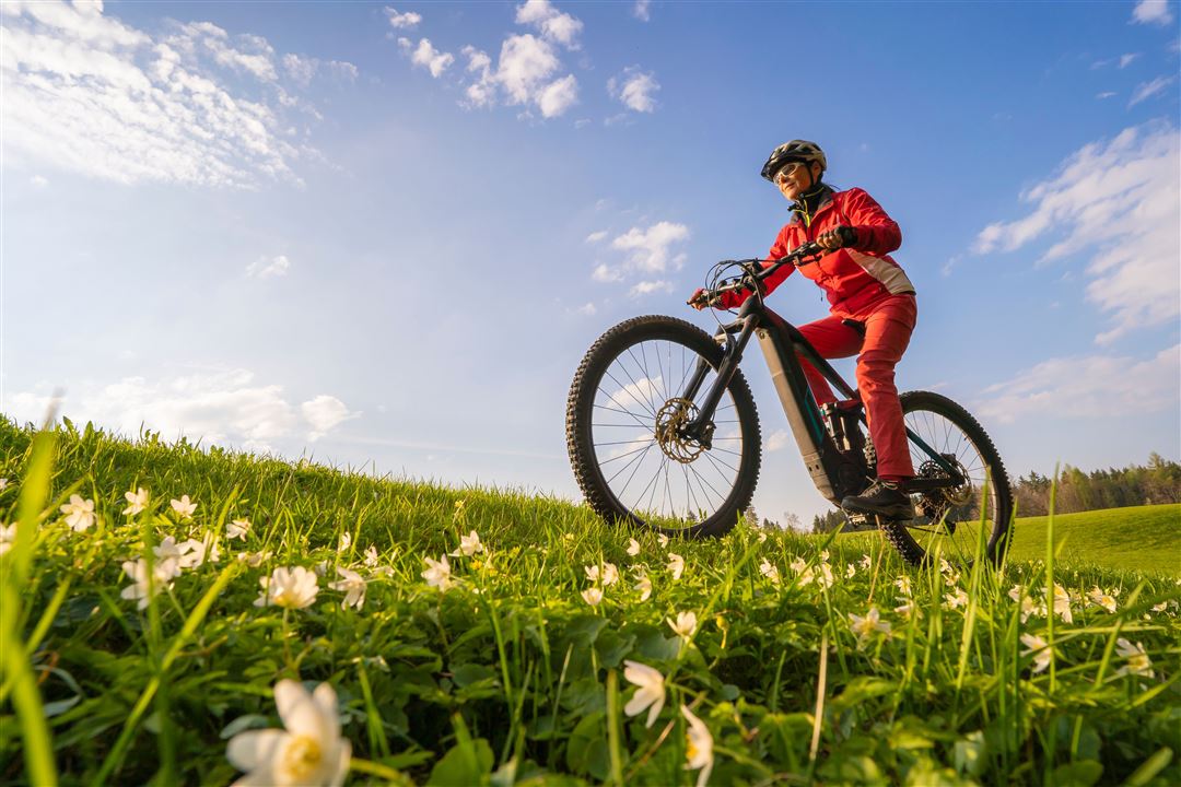 Frau f&auml;hrt mit ihrem E-Bike &uuml;ber eine Wiese