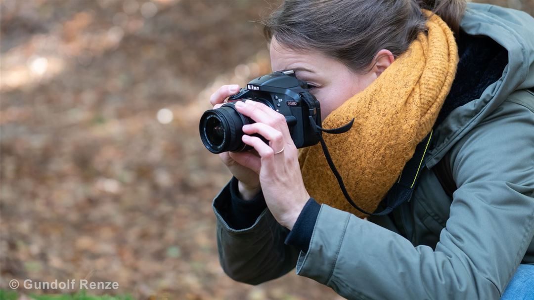 Person fotografiert mit Nikon-Kamera drau&szlig;en