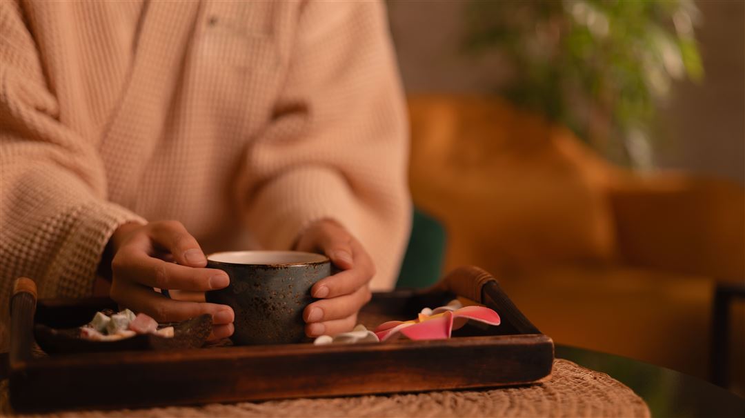 Nahaufnahme von H&auml;nden einer Frau an einer Teetasse