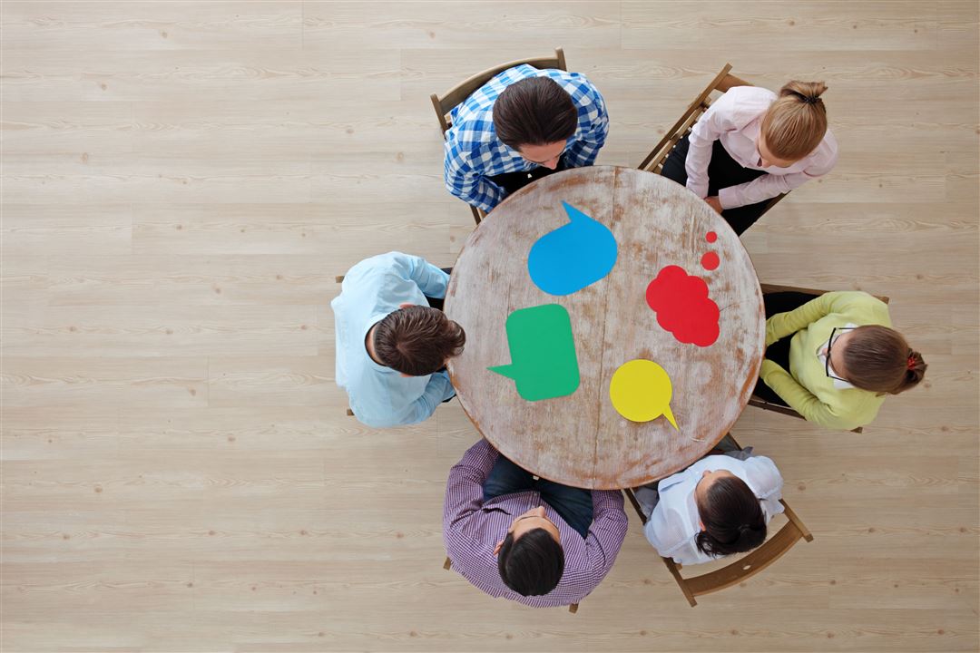 Menschen sitzen im Austausch um einen Tisch herum