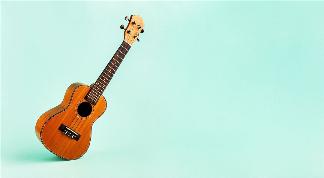 Eine Ukulele vor t&uuml;rkisem Hintergrund.