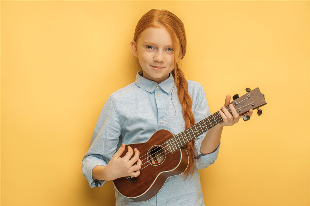 M&auml;dchen mit Ukulele vor gelbem Hintergrund