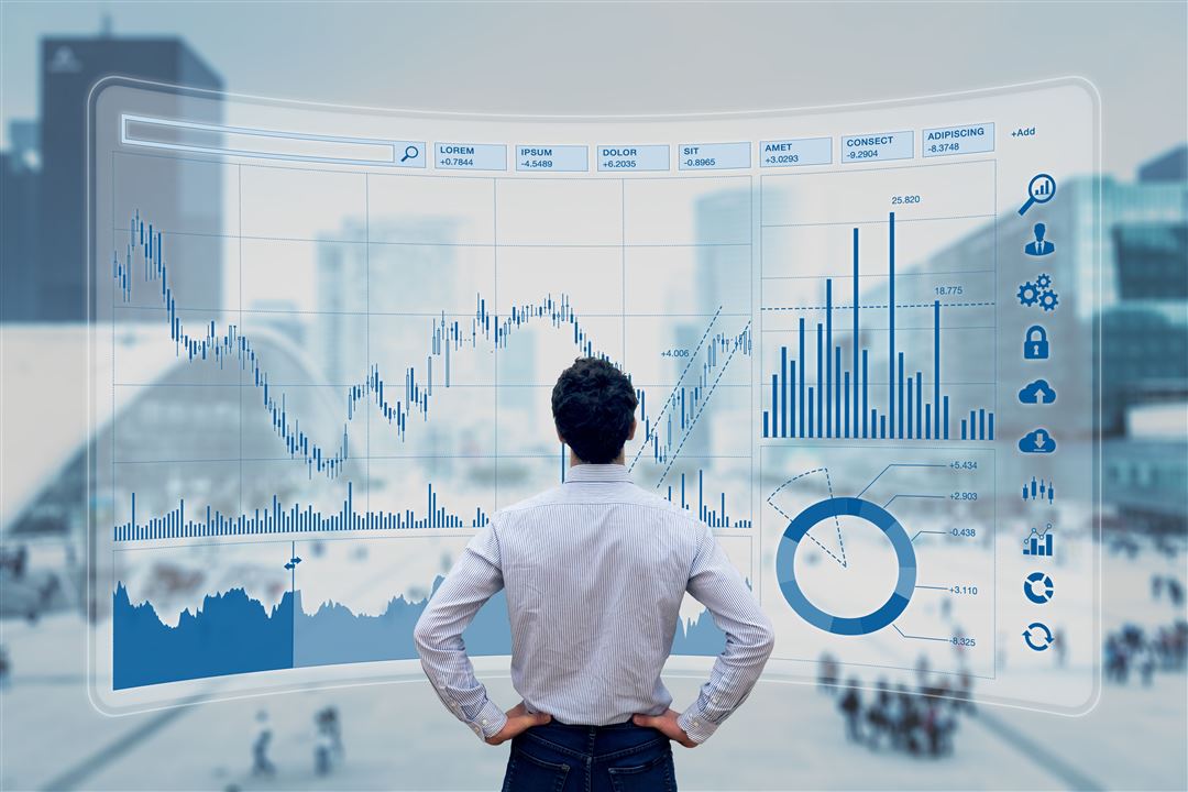 Person vor Bildschirm mit Finanzdiagrammen in urbaner Umgebung.